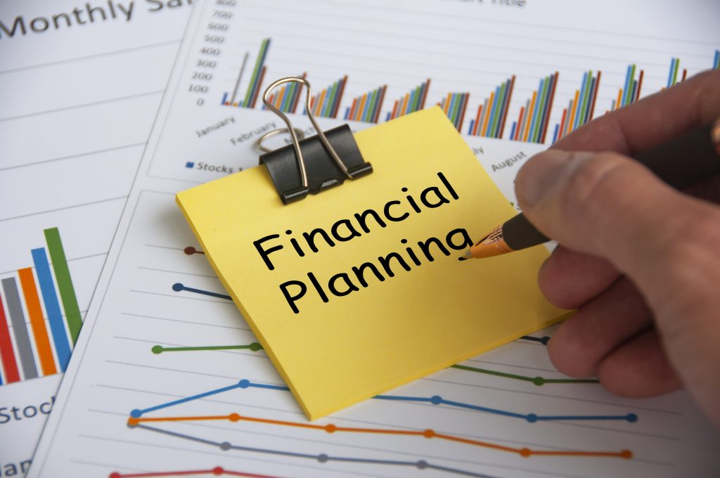 Financial planning text on yellow notepad with financial data analysis background. Financial planning concept.